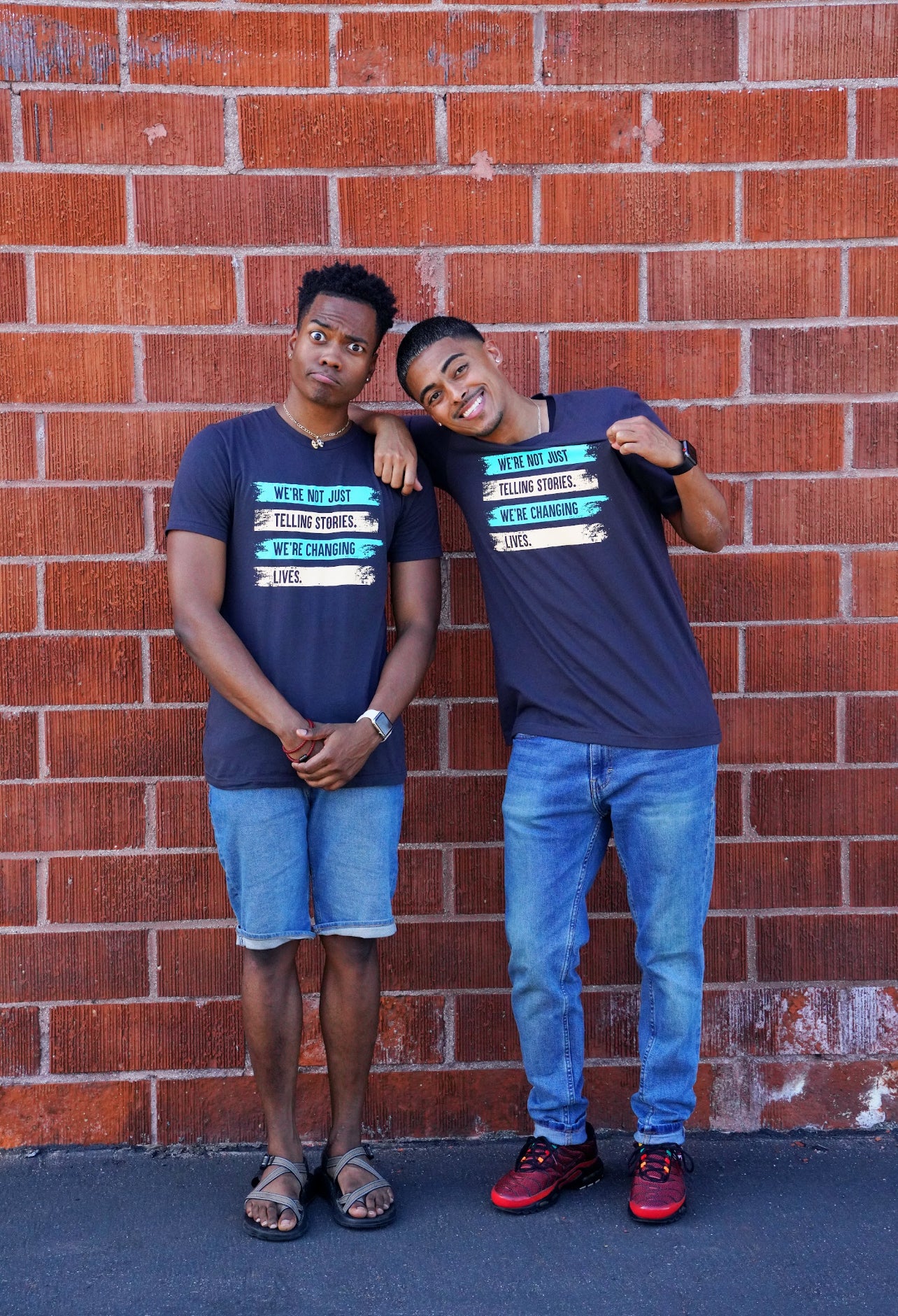 Nick and Alexis show off the Two-Tone Changing Lives T-shirt as they pose in front of a brick wall