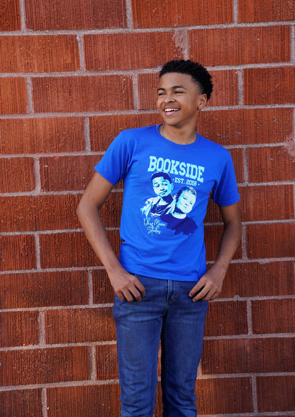 Shaun (Jay) wears the Jay & Mikey Bookside High T-shirt while hanging out in front of a brick wall